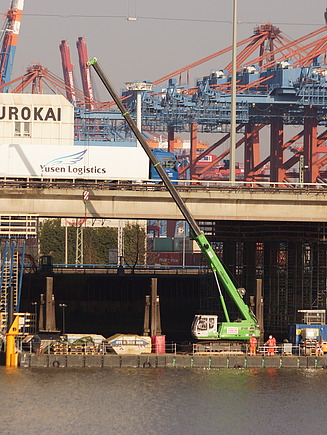 Foto einer Brücke mit Hafengelände im Hintergrund