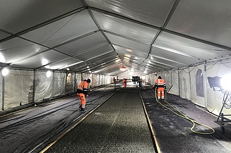 Foto mehrerer Personen in einem Zelt auf einer Fahrspur