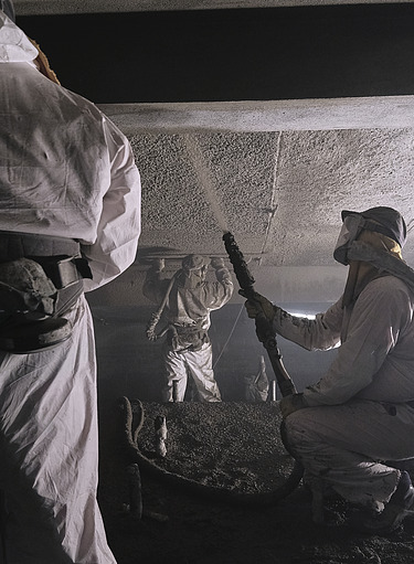 Foto von zwei Personen im Schutzanzug und einer Spritzbeton-Handlanze