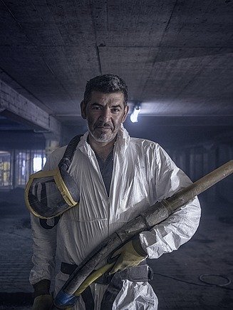 Foto von einem Mann in weißen Kittel und Spritzbetonlanze in der Hand