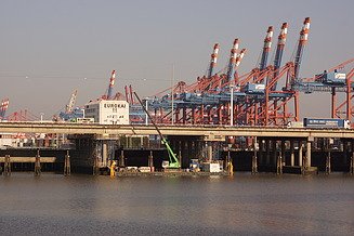 Foto einer Brücke mit grünem Kran und Hafen im Hintergrund