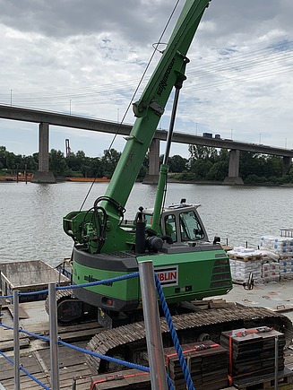 Foto eines grünen Kranes mit einer Brücke im Hintergrund