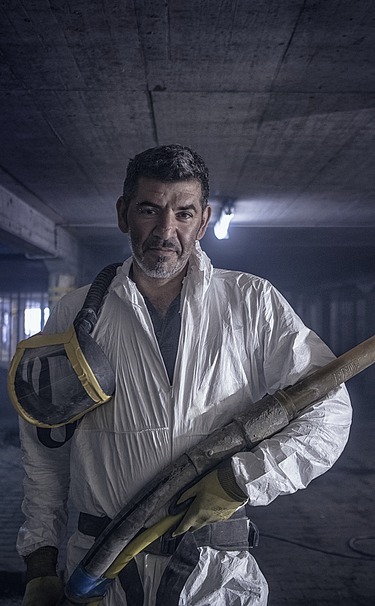 Foto von einer Person mit weißer Schutzkleidung und einer Spritzlanze