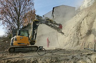 Foto von einem Bagger und einer Person an einer Baugrube