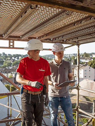 Foto von zwei Personen mit Helm auf einem Gerüst