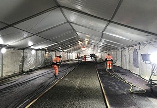 Foto mehrerer Personen in einem Zelt auf einer Fahrspur